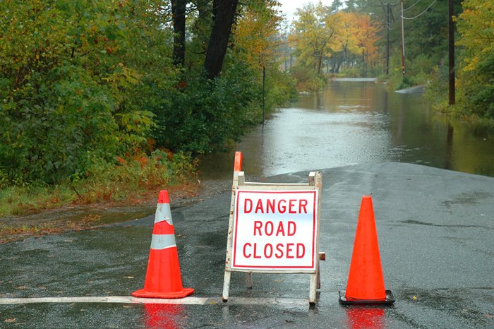 A street flooded with traffic cones and a road closed sign.