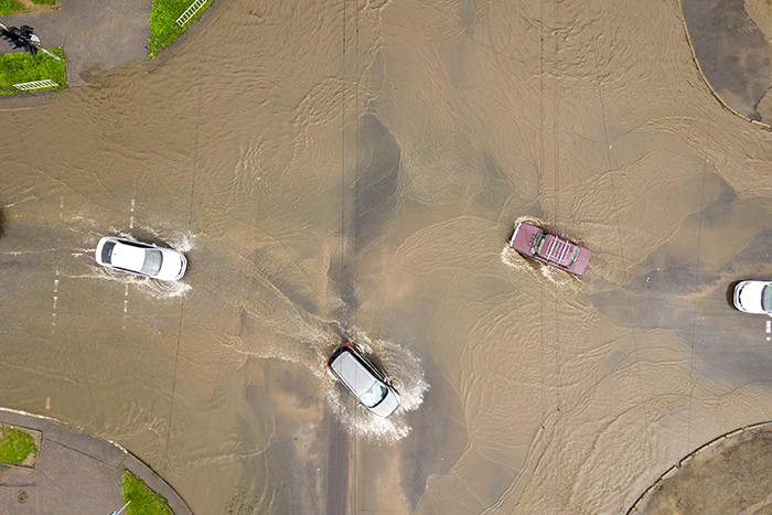Aerial view of three cars driving through a flash flood.