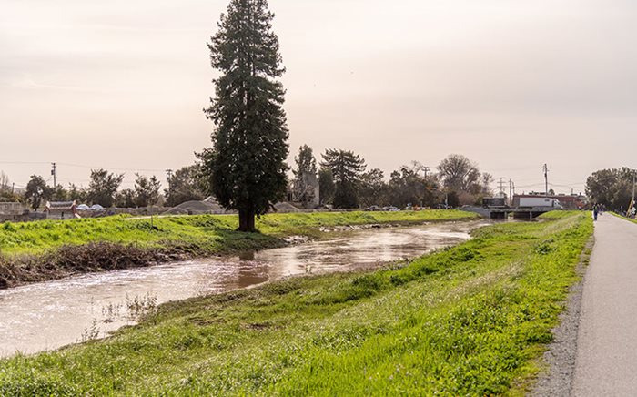 a flooded river next to the side of a road and community.