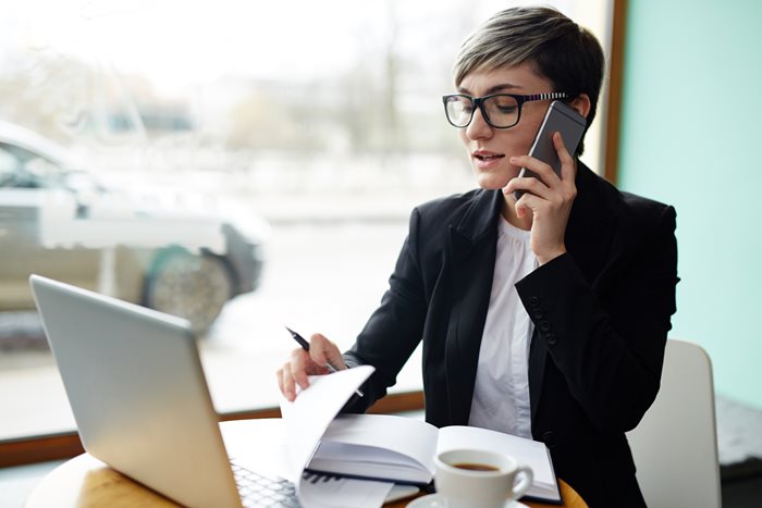 A woman on the phone conducting business looking at her laptop.