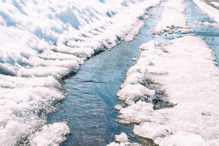 A stream of melting snow on asphalt.