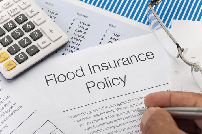notepad with expenses along with calculator and flood insurance policy document